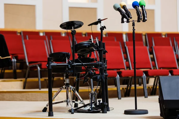 スタンドにはカラーマイク 表彰台には電子ドラムセットが設置されており 背景にはたくさんの赤い椅子がぼやけています コンサート イベント コミュニケーション セミナー メディア パフォーマンスの概念 — ストック写真