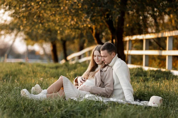 母の日 赤ちゃんを待っているスタイリッシュな結婚の妊娠中のカップル 男は抱擁し 芝生の上で再生された女性の腹を屋外に触れます 家族の日だ 家族の概念 — ストック写真