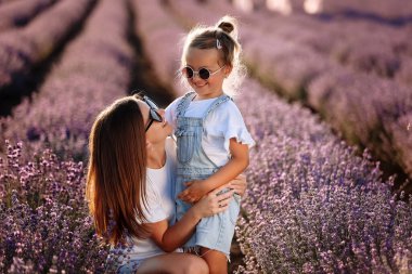 Mor lavanta tarlasında mutlu bir aile. Genç, güzel anne ve çocuk kız yaz günü çiçek açan çayırlarda yürümenin keyfini çıkarıyorlar. Anne gün batımında doğada güzel kızıyla eğleniyor. Anneler Günü.