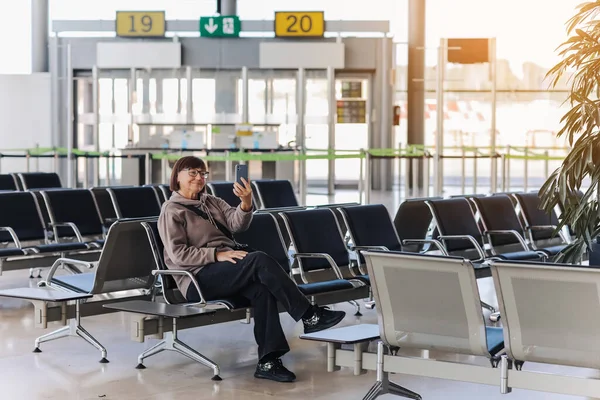 여행자는 터미널에 출발하기 비행기에 탑승하기를 기다리는 스마트폰을 무료로 여행하는 동안새로운 — 스톡 사진