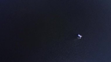 Şişme yatakta kimliği belirsiz bir adamın havadan aşağı görüntüsü güneşli bir günde açık mavi deniz suyunda güneşlenmeyi seviyor. Yaz tatili ve tatil konsepti. Boşluğu kopyala.