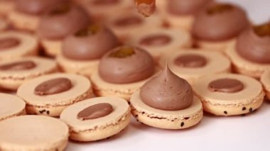 Şefin ellerinin çikolatalı badem kabuğuna fındıklı tuzlu karamelli ganache kreması koyması. Makarna Fırını Konsepti. Pişirme, Yemek ve Pişirme Konsepti. Şekerleme ve Pişirme Konsepti