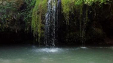 Vahşi şelalenin manzarası ve orman ortamında zümrüt su gölü havuzu. Ağaçların arasında parlayan güneş ışığıyla tropikal doğa. Seyahat yeri.