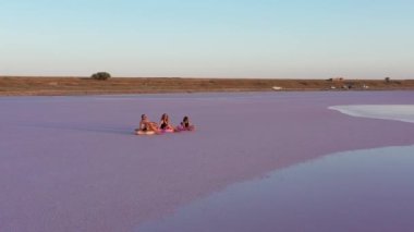 Mutlu yaz tatilleri. Anne, baba ve çocuğun silueti deniz kıyısında birlikte eğleniyor ve güzel günbatımında şamandıralarda oturuyor. Babalar Günü, Anneler Günü, Bebek Günü.