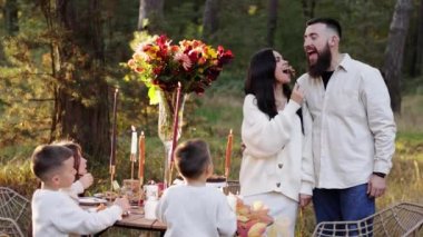 Mutlu aile günleri. Anne, baba ve üç küçük çocuk pikniğe gider. Şükran Günü şenlik masasında çiçek buketi ve sonbahar parkında mum yakarlar. Genç kadın, erkeği ev yapımı turtayla besler..