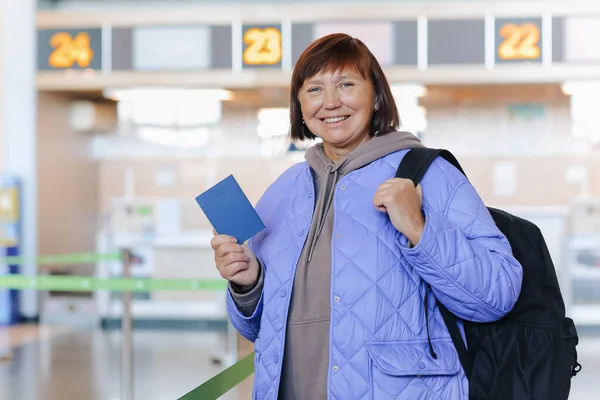 여행객 가방을 여권을 터미널에서 비행기를 기다리고 중년의 여성은 휴가를 즐기기 — 스톡 사진