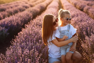 Mor lavanta tarlasında mutlu bir aile. Genç, güzel anne ve çocuk kız yaz günü çiçek açan çayırlarda yürümenin keyfini çıkarıyorlar. Anne gün batımında doğada güzel kızıyla eğleniyor. Anneler Günü.