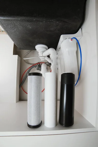 House water filtration system to drinkable condition, reverse osmosis. Filter cartridges of foamed polypropylene, granular and briquettes carbon under kitchen sink. Installation or replacement.
