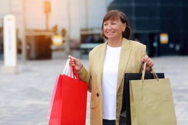 Mevsimlik satışlar. Alışveriş torbalı mutlu yetişkin kadın. Alışveriş merkezinden alışveriş yaptıktan sonra orta yaşlı bir kadın. Satın alma, indirim, satış konsepti. İnternetten alışveriş konsepti, Kara Cuma. maketleme.
