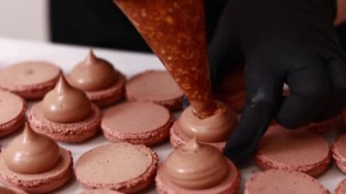 Şefin ellerinin çikolatalı badem kabuğuna fındıklı tuzlu karamelli ganache kreması koyması. Makarna Fırını Konsepti. Pişirme, Yemek ve Pişirme Konsepti. Şekerleme ve Pişirme Konsepti