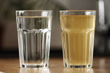 Ev suyu filtreleme sistemi içilebilir durumda. Ters ozmos filtrelemesinden sonra bir bardak temiz su ve mutfaktaki masanın üstünde bir bardak kirli su. Musluk suyunun kirlendiğine dair kanıt.