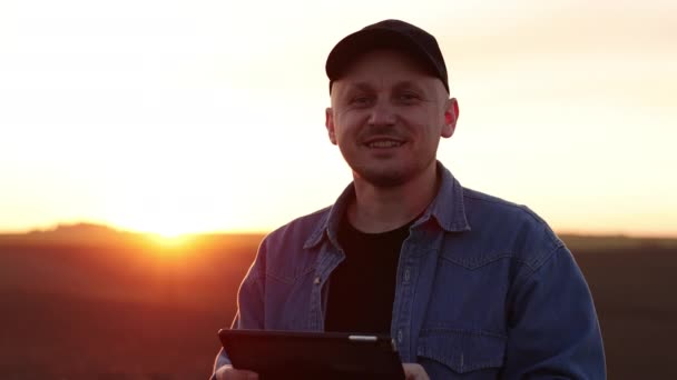 Uśmiechnięty Rolnik Trzyma Cyfrową Tabletkę Polu Zaoraną Ziemią Zachodzie Słońca — Wideo stockowe