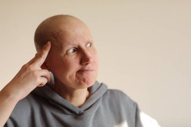 Yüz ifadeleri ve duygular. Düşünceli, kel bir kadın evde el ele tutuşup kuşkulu bakışlar atarak sıradan bir kazak giyiyor. Sağlık sorunları, kanser, saç dökülmesi. Boşluğu kopyala.