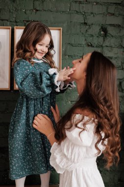 Anneler Günü. Duyarlı genç anne, sevimli kızını evinde kucaklıyor. Anneyle çocuk arasındaki güven, destek ve sevgi. Sevgi dolu aile, tatlı anların ve sıkı sarılmaların tadını çıkarır. Çocuk günü.