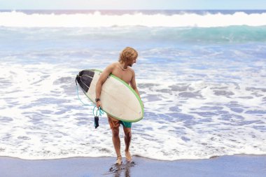 Sörf tahtası olan genç bir sörfçü sörf yapmak için büyük dalgalarla okyanusa ya da denize koşar. Ekstrem spor, fitness, özgürlük, mutluluk, yeni modern hayat kavramı. Spor gezisi hedefi