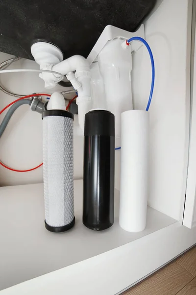 House water filtration system to drinkable condition, reverse osmosis. Filter cartridges of foamed polypropylene, granular and briquettes carbon under kitchen sink. Installation or replacement.