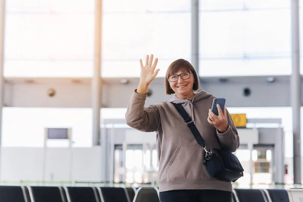 Ευτυχισμένο Χαμόγελο Ώριμη Ταξιδιώτη Γυναίκα Κατέχουν Smartphone Και Χέρι Κύμα — Φωτογραφία Αρχείου