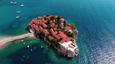Karadağ 'ın güzel bir yaz gününde Sveti Stefan adası ve kıyılarının havadan görünüşü, insansız hava aracı uçurmaktan. Aziz Stephen 'ın lüks tatil köyünün üstündeki panoramik. Turizm ve eğlence kavramı. Videografi:.
