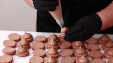 Fransız çöl kurabiyeleri yapıyorum. Pastanedeki kahverengi çikolatalı kurabiyelerin hazır yarımlarına krema ekleyen şefin elleri. yemek, yemek ve pişirme konsepti