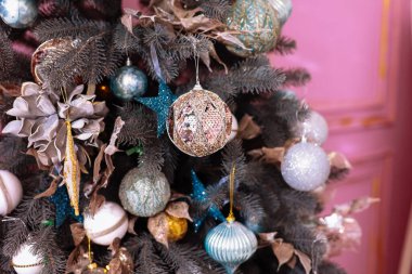 Parlak gümüş ve mavi mücevher, top, yıldızlar, xmas süslemeleri ve ışıklarla süslenmiş göz kamaştırıcı yapay köknar dallarına yakından bakın. Pembe duvar. Noel tatili geçmişi. Şenlikli yeni 2024 yılı.
