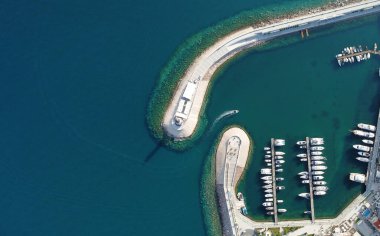 Ahşap rıhtımların yakınındaki yat kulübünde lüks yelkenli yatları ve tekneleri gösteren hava manzarası. Avrupa 'nın en iyi manzarası. Deniz kıyısına yakın büyük bir tekne parkı. Deniz fenerine giden yol. Yaz konseptinde yat.