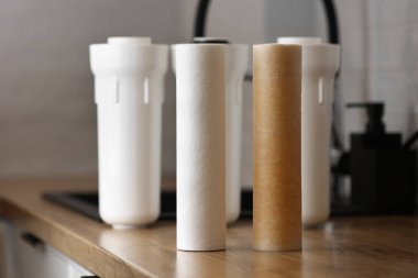 Yerli su kaynakları için su arıtma. Yeni temiz ve kullanılmış su filtresi paslı mutfak masasında. Musluk suyunun demir parçalarıyla kirlendiğine dair kanıt. Ev filtrelemesi.