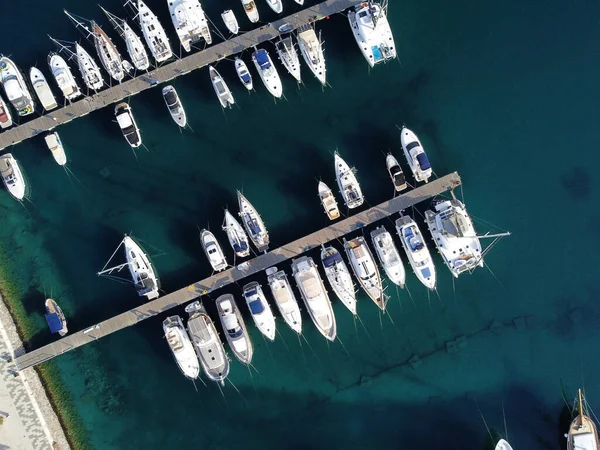 Aerial view of luxury sailing yachts and boats in yacht club near wooden piers. Top view of european city. Large boat parking near sea coast. Road to the lighthouse. Yachting in summer concept