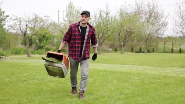 Gardener Άνθρωπος Casual Ρούχα Μεταφέρει Πλαστικό Χλοοκοπτικό Κουτί Κομμένο Γρασίδι — Αρχείο Βίντεο