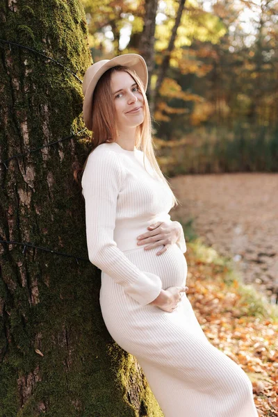 Элегантная Молодая Беременная Женщина Белом Вязаном Платье Шляпе Прикасаясь Гладя — стоковое фото