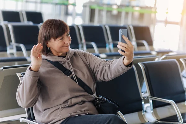 여행자는 스마트폰을 비디오 전화를 손으로 파도를 나이든 블로거나 블로거는 터미널에서 — 스톡 사진