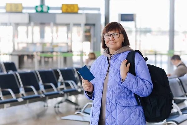 여행객 가방을 여권을 터미널에서 비행기를 기다리고 중년의 여성은 휴가를 즐기기 — 스톡 사진