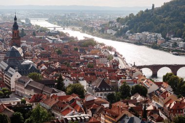 Neckar nehri üzerinde köprüsü olan ünlü Heidelberg Almanya şehri üzerinde hava aracı görüntüsü. Eski kasaba ve dağların üzerinde güneş ışınlarıyla dramatik bulutlu gökyüzü.