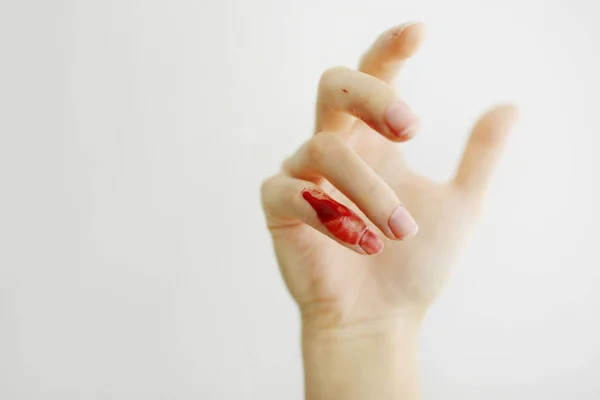 Female hand with red blood, little finger is bleeding profusely. Woman injured her little finger at home with knife or other sharp object. Bleeding wound and body injury result. Domestic accident