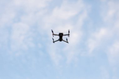 Beyaz bulutlu mavi gökyüzünde uçan bir dron. Dijital kameralı alt görüntü kuadkopteri. Uzaktan kumandalı kuadrokopter, UAV