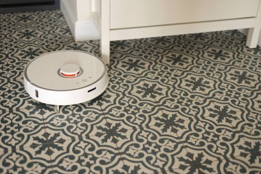 Kablosuz özerk akıllı robot elektrikli süpürge oturma odasındaki modern fayanslarla yerleri süpürüyor. Otomatik itişli temizlik robotu. Yer temizleme sistemi. Ev kumandası aygıtları