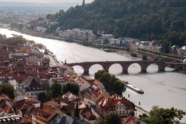 Neckar nehri üzerinde köprüsü olan ünlü Heidelberg Almanya şehri üzerinde hava aracı görüntüsü. Eski kasaba ve dağların üzerinde güneş ışınlarıyla dramatik bulutlu gökyüzü.