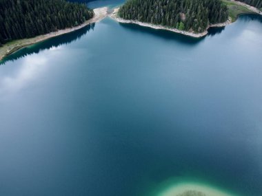 Crno Jezero veya Kara Göl, çam ormanı ve Karadağ 'ın Zabljak kentindeki Durmitor ulusal parkındaki uçurumların inanılmaz hava aracı görüntüsü. Seyahat, çevre, doğa güzelliği, rahatlatıcı. UNESCO Dünya Mirası.