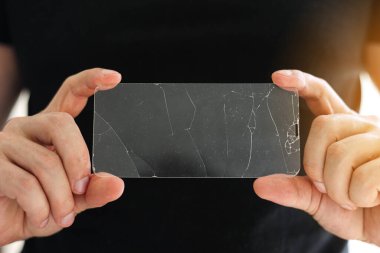 Siyah arka plandaki telefon tamircisinin elinde akıllı telefon ekranı için kırılmış koruyucu cam. Hasarlı camları yapıştırma ve değiştirme hizmetleri. Onarım kavramı.