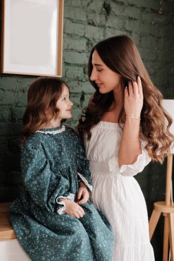 Anneler Günü. Duyarlı genç anne, sevimli kızını evinde kucaklıyor. Anneyle çocuk arasındaki güven, destek ve sevgi. Sevgi dolu aile, tatlı anların ve sıkı sarılmaların tadını çıkarır. Çocuk günü.