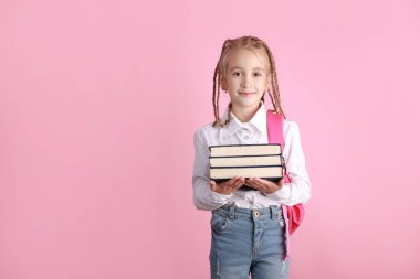 1 Eylül 'de okula dönüş konsepti. Gülümseyen liseli kız ve sırt çantası pembe arka plan üzerine kitaplar tutuyor. Sevimli çocuk kameraya bakıyor. Çocukluk yaşam tarzı konsepti. Okulda eğitim.