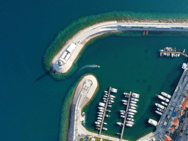 Ahşap rıhtımların yakınındaki yat kulübünde lüks yelkenli yatları ve tekneleri gösteren hava manzarası. Avrupa 'nın en iyi manzarası. Deniz kıyısına yakın büyük bir tekne parkı. Deniz fenerine giden yol. Yaz konseptinde yat.