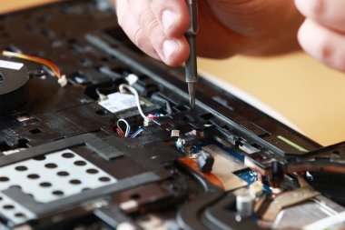 Parçalanmış dizüstü bilgisayar parçalarını tamir eden tornavidayla tamirci. Teknik destek ve alet tamir sorunları. Bakım, onarım, temizlik, bilgisayar bakımı. Tamirci. Donanım maintenanc.