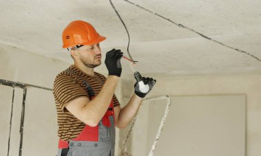 Üniformalı elektrik, koruyucu eldivenler ve tornavida ile elektrik voltajının kontrol edilip ölçülmesi. Yeni binadaki kabloları voltaj dedektörüyle inceliyorum..