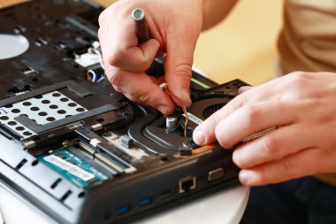 Parçalanmış dizüstü bilgisayar parçalarını tamir eden tornavidayla tamirci. Teknik destek ve alet tamir sorunları. Bakım, onarım, temizlik, bilgisayar bakımı. Tamirci. Donanım maintenanc.
