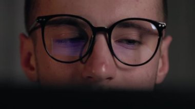 Bilgisayar gözlüklü programcının odaklanmış genç yüzünü ekranların yansımasıyla çevrimiçi olarak kapat. Ciddi bir hacker, dizüstü bilgisayar kullanan bir bilişim uzmanı. Sanal yarışmada Esport oyuncusu.