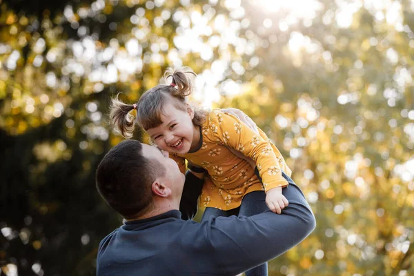 Happy fathers day. Joyful dad throws up his little smiling daughter at autumn park. Single daddy and child have fun, laugh and enjoy nature. Concept of parental care and happy carefree childhood.