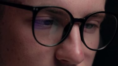 Bilgisayar gözlüklü programcının odaklanmış yüzünü ekranların yansımasıyla çevrimiçi olarak kapat. Konsantre hacker, dizüstü bilgisayar kullanan bilişim uzmanı. Sanal yarışmada Esport oyuncusu.