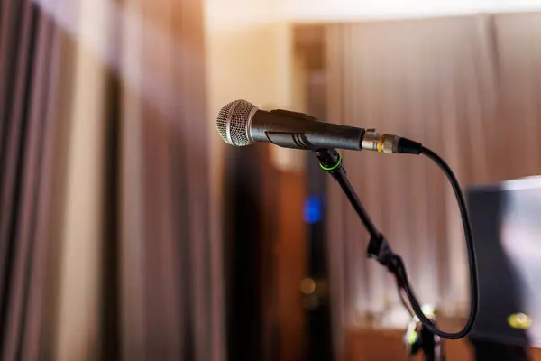 Microphone on stand on stage close up with searchlight light. Professional mic at concert hall or conference room, karaoke, night club, bar. Public events, festival, wedding. Copy space