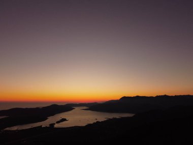 Kotor, Adriyatik, Karadağ 'daki Kotor Körfezi' nde güzel gün batımı veya gündoğumu manzaralı hava aracı manzarası. Parlak turuncu güneş ışığıyla sakin bir ufuk çizgisi. Yaz tatili kavramı.