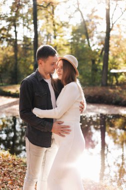 Genç şık çift aşıkları sonbahar parkında sarılıyorlar. Aşık bir erkek ve kadın arasında romantik bir an. Mutlu bir aile. Aşk, gençlik, mutluluk konsepti